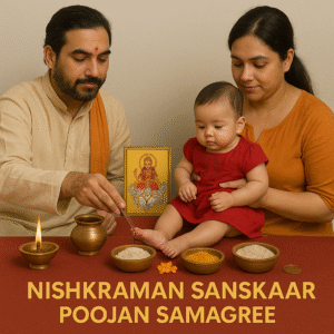 A traditional Hindu Nishkraman Sanskaar Poojan setup showing a priest performing a ritual for an infant held by the mother, with sacred items like diya, rice, turmeric, kumkum, Surya Dev image, and copper kalash arranged on a red cloth, symbolizing the baby’s first outing ceremony.