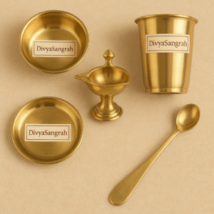 "Set of Panch Bartan traditional brass puja utensils by DivyaSangrah, including plate, bowl, spoon, tumbler, and diya, displayed on a beige background for Hindu rituals."